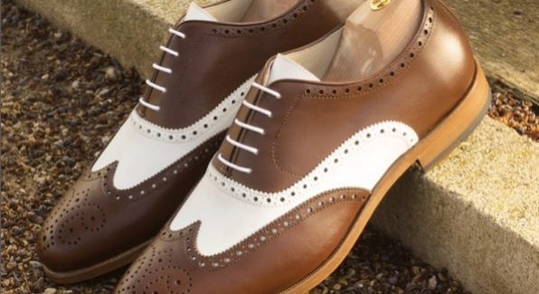 Glad leren herenschoen in wit en bruin met brogues. De schoen heeft witte veters en wordt getoond met houten schoenspanner.